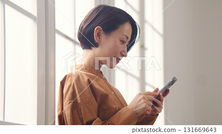 一位女士在窗邊使用手機 131669643