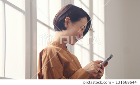一位女士在窗邊使用手機 131669644