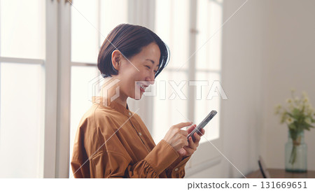 A woman using a phone by the window 131669651