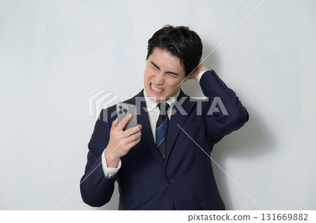 A man in a suit looking at his smartphone 131669882