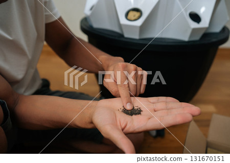 Close-up view of gardener touching small hydroponic seeds in n open hand, preparing to plant in hydroponic tower system with rockwool, showcasing modern and sustainable agriculture. Close-up view of gardener touching small hydroponic seeds in n open hand, preparing to plant in hydroponic tower system with rockwool, showcasing modern and sustainable agriculture. 131670151