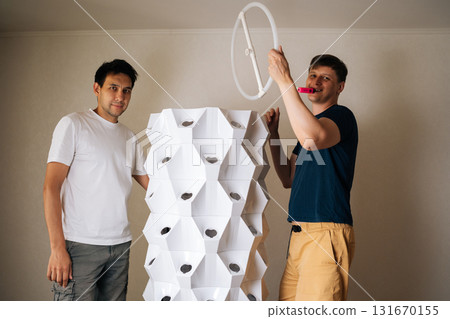 Portrait of agricultural engineers assembling vertical hydroponic tower, showcasing modern approach to indoor farming that merges technology with sustainable practices for efficient food production. 131670155