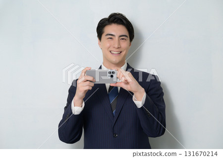 A man in a suit holding a smartphone on a white background A man in a suit holding a smartphone on a white background 131670214