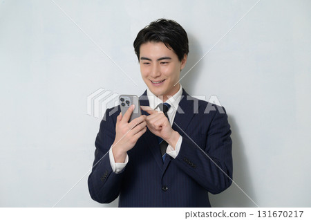 A man in a suit holding a smartphone on a white background 131670217