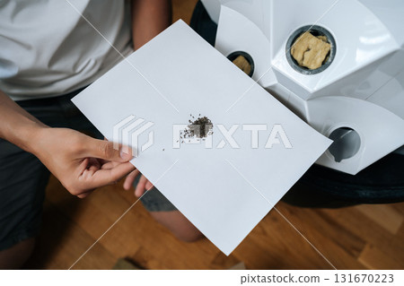 Agricultural technician holding paper with seeds, preparing for planting in modern hydroponic system with rockwool and hydroponic tower in background. Concept of healthy and sustainable cultivation. 131670223