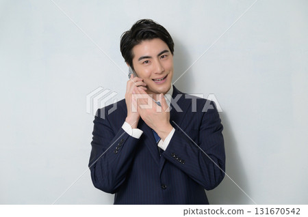 一位身穿西裝的男子在白色背景下打電話 131670542