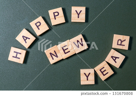 Wooden letter tiles spelling Happy New Year arranged neatly on a textured green background 131670808