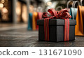 black gift box with red bow, along with other brightly colored shopping bags, perfect for shopping at the mall. Holiday and seasonal sales, gift shopping, online shopping, Black Friday, Cyber Monday. 131671090