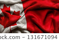 Close-up of the Canadian flag with a textured fabric surface, showing the iconic red maple leaf and vibrant red and white colors, symbolizing national pride and patriotism 131671094