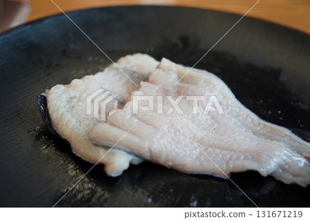 Fresh Raw Eel Fillets on a Black Plate, Ready for Cooking 131671219