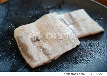 Fresh Raw Eel Fillets on a Black Plate, Ready for Cooking 131671220
