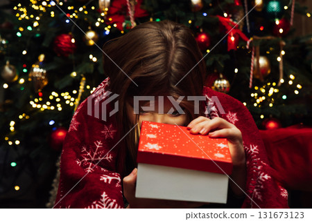 Christmas Surprise Moment with Gift Box. Excited Child Holding Red Christmas Present. holiday excitement, winter warmth, and joyful seasonal celebration Christmas Surprise Moment with Gift Box. Excited Child Holding Red Christmas Present. holiday excitement, winter warmth, and joyful seasonal celebration 131673123