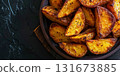 Deliciously roasted potato wedges served in a rustic bowl on a dark textured surface 131673885