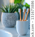 Natural bamboo toothbrushes in a stylish holder next to green plants in a modern bathroom setting during daylight 131673886