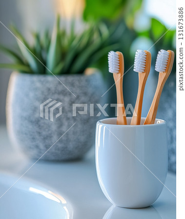 Natural bamboo toothbrushes in a stylish holder next to green plants in a modern bathroom setting during daylight 131673886