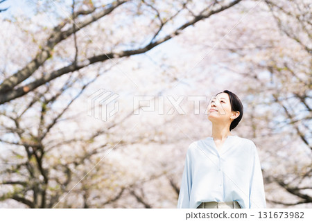 Young woman looking up at cherry blossoms Lifestyle image 131673982