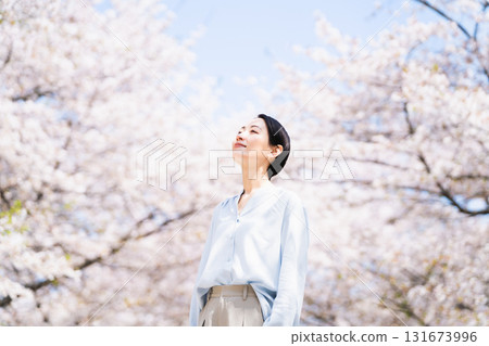 Young woman looking up at cherry blossoms Lifestyle image 131673996