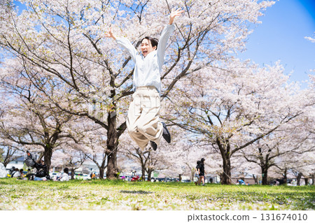 Young woman jumping under a row of cherry blossom trees Lifestyle image Young woman jumping under a row of cherry blossom trees Lifestyle image 131674010