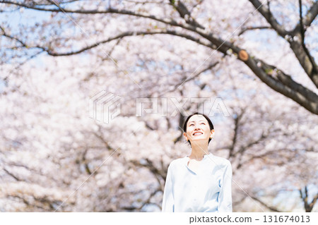 A young woman looking up at the cherry blossom trees Lifestyle image 131674013