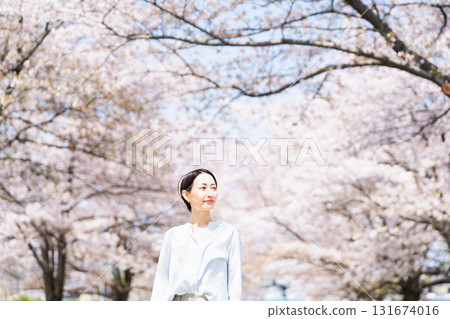 A young woman looking up at the cherry blossom trees Lifestyle image 131674016