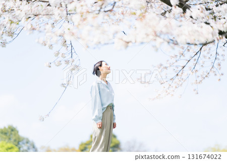 Young woman looking up at the cherry blossom tree Lifestyle image 131674022