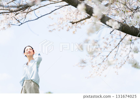 Young woman looking up at the cherry blossom tree Lifestyle image Young woman looking up at the cherry blossom tree Lifestyle image 131674025