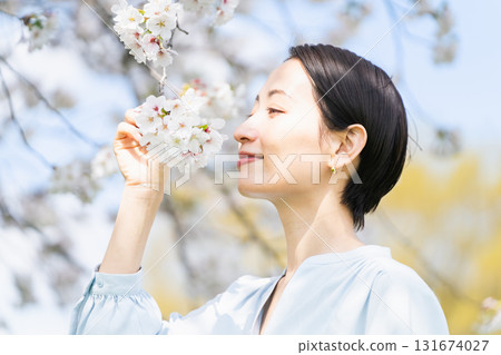 Young woman looking at cherry blossom petals Lifestyle image Young woman looking at cherry blossom petals Lifestyle image 131674027