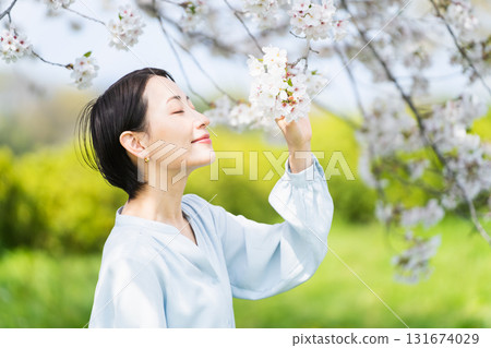 Young woman looking at cherry blossom petals Lifestyle image 131674029