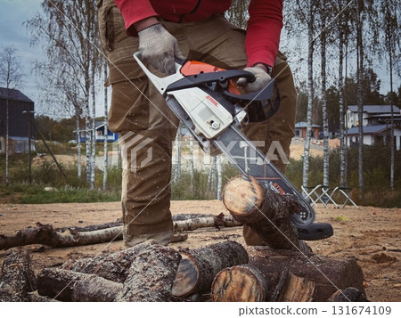 close up photo of A man cutting a log into firewood using a chainsaw close up photo of A man cutting a log into firewood using a chainsaw 131674109