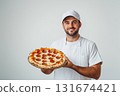 Smiling pizza chef showcases freshly baked pepperoni pizza in a bright kitchen environment 131674421