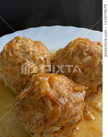 Three steaming meatballs with sauce on plate. Meatballs with rice and onions simmered in tomato sauce. Delicious and healthy home cooking. 131674679