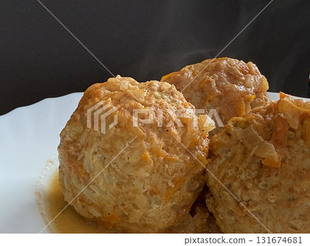 Three steaming meatballs with sauce on plate. Meatballs with rice and onions simmered in tomato sauce. Delicious and healthy home cooking. Three steaming meatballs with sauce on plate. Meatballs with rice and onions simmered in tomato sauce. Delicious and healthy home cooking. 131674681