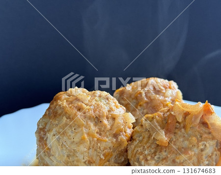 Three steaming meatballs with sauce on plate. Meatballs with rice and onions simmered in tomato sauce. Delicious and healthy home cooking. 131674683