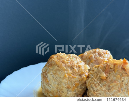 Three steaming meatballs with sauce on plate. Meatballs with rice and onions simmered in tomato sauce. Delicious and healthy home cooking. Three steaming meatballs with sauce on plate. Meatballs with rice and onions simmered in tomato sauce. Delicious and healthy home cooking. 131674684