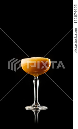 Amber cocktail with foamy top in classic coupe glass on black 131674695