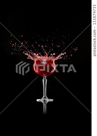 Red foamy cocktail splash captured in dramatic motion on black background 131674733
