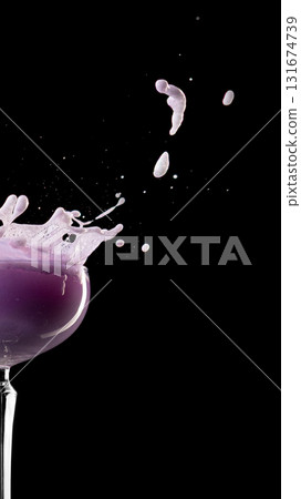 Purple cocktail splash with foam and droplets on black background Purple cocktail splash with foam and droplets on black background 131674739