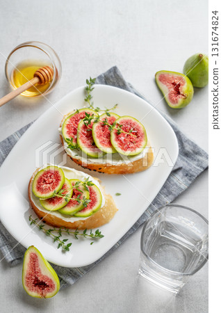Sweet toasts with fresh figs, cheese, thyme, and honey on a light background. 131674824