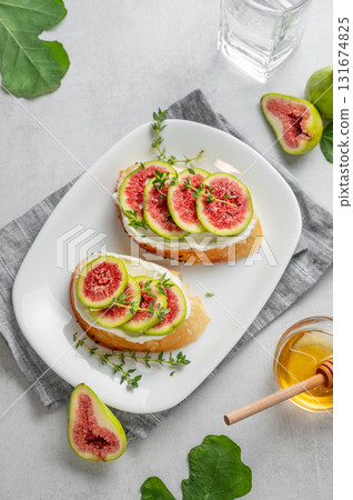 Sweet toasts with fresh figs, cheese, thyme, and honey on a light background. 131674825