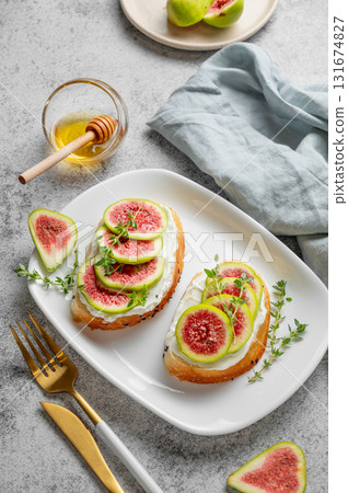 Sweet toasts with fresh figs, cheese, thyme, and honey on a gray background. Sweet toasts with fresh figs, cheese, thyme, and honey on a gray background. 131674827