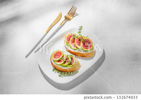 Sweet toasts with fresh figs, cream cheese, thyme, and honey on a light background. 131674833