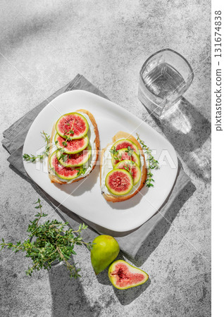 Sweet toasts with fresh figs, cream cheese, thyme, and honey on a gray background. Sweet toasts with fresh figs, cream cheese, thyme, and honey on a gray background. 131674838