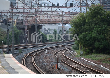 A landscape with curved rails and a station platform 131675858