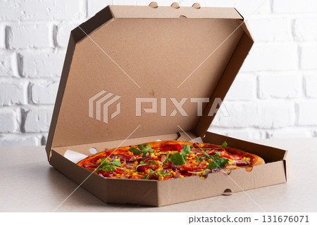 Large Pizza in open carton box on kitchen table closeup view 131676071
