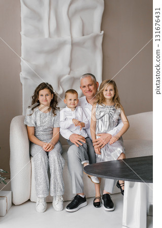 Happy family of four, including man and three children, are sitting on couch in room Happy family of four, including man and three children, are sitting on couch in room 131676431