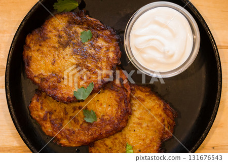 Fried grated potato pancakes with sour cream on frying pan. top of view 131676543