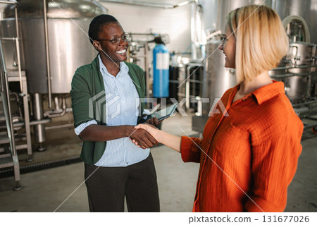 Two businesswomen making a deal, shaking hands in industrial setting Two businesswomen making a deal, shaking hands in industrial setting 131677026