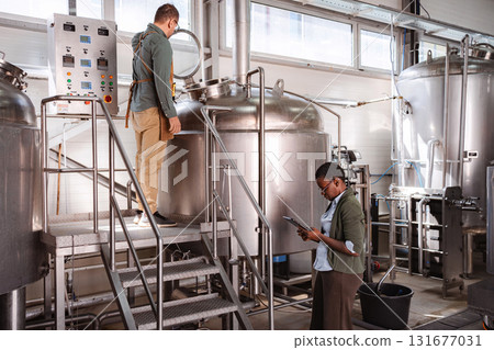 Brewery workers inspecting production quality control with digital tablet Brewery workers inspecting production quality control with digital tablet 131677031
