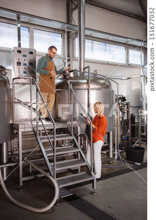 Brewery workers monitoring beer brewing process 131677032