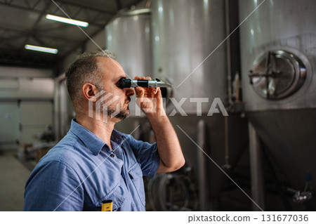 Man using refractometer checking beer quality at brewery 131677036